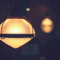 "Vintage glass pendant light fixture with warm illumination in dark restaurant setting"